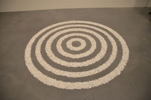 Concentric circles made of white pebbles on a gray floor.