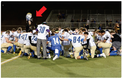 Group of football players and coach praying.