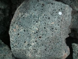 Dark grey rock with many visible holes and no visible crystals.