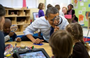 President Obama is sitting down as he interacts with children